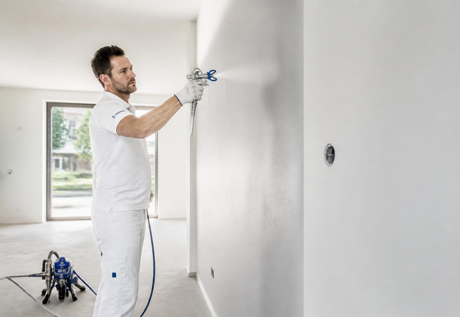 Vakman spuit een wand met een airless spuitinstallatie